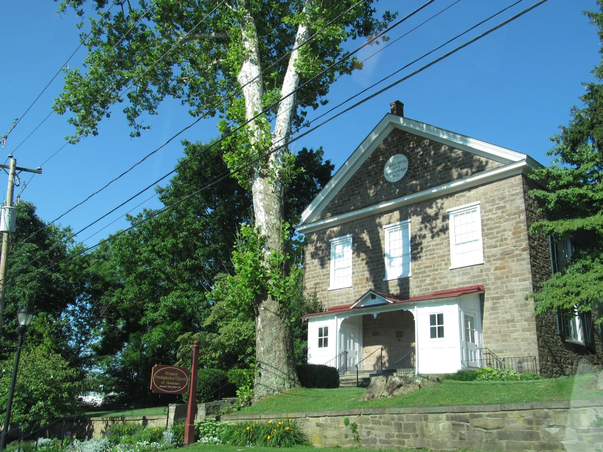 Historic stone Presbyterian church of Newtown behind a sycamore tree